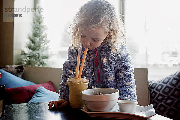 Mädchen trinkt Kaffee  während sie zu Hause am Fenster sitzt