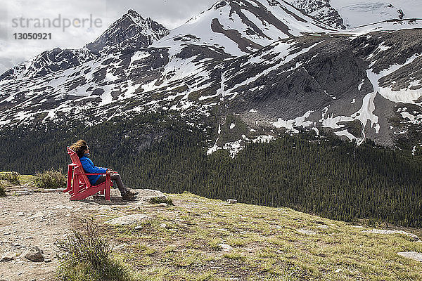 Wanderer schaut auf Aussicht  während er sich auf einem Stuhl an den Bergen ausruht