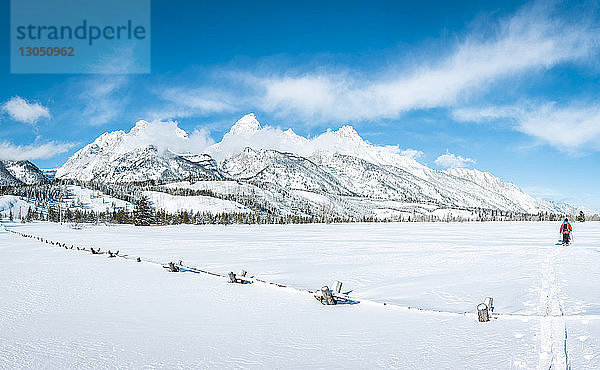 Männer gehen auf Feld gegen schneebedeckten Berg