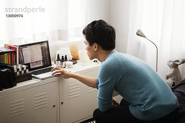 Seitenansicht eines Mannes mit Laptop im Schlafzimmer