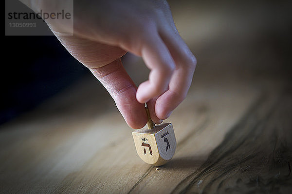 Abgehackte Hand eines Mannes  der Dreidel auf dem Tisch dreht