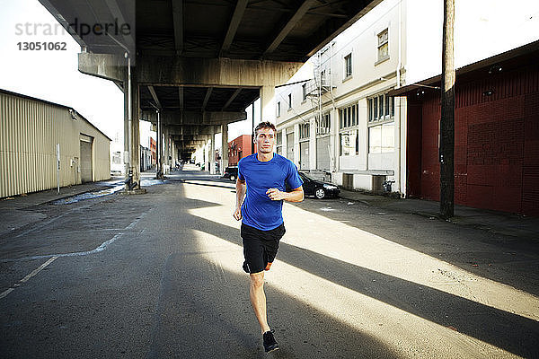 Mann joggt auf Stadtstraße unter Brücke