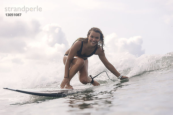 Porträt einer sorglos lächelnden Frau beim Surfen im Meer