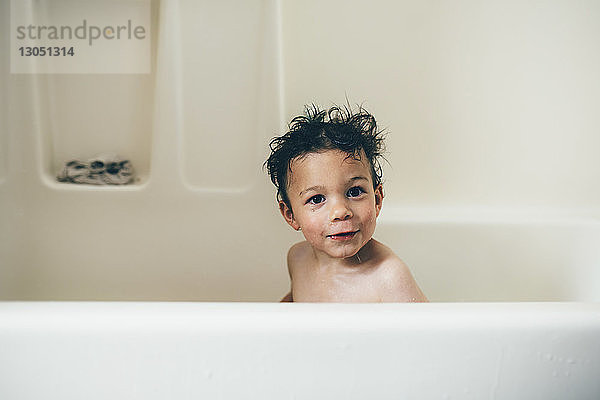 Porträt eines hemdlosen  nassen Jungen  der zu Hause in der Badewanne sitzt