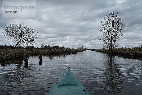 Kajak im Fluss gegen bewölkten Himmel