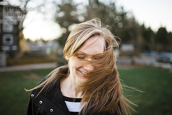 Fröhliches Teenager-Mädchen wirft Haare im Park