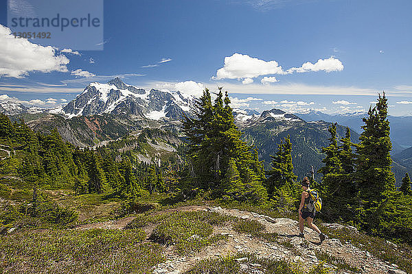 Wanderin in voller Länge  die im Winter im North Cascades National Park gegen Berge und Himmel wandert