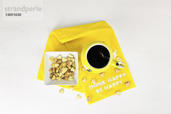 Draufsicht einer herzförmigen Speise von einer Teetasse auf gelber Serviette auf weißem Hintergrund