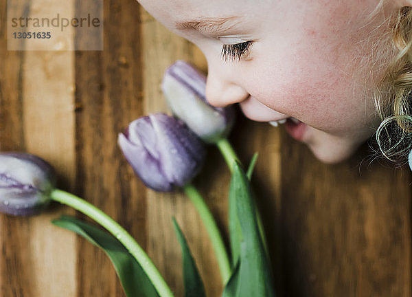 Hochwinkelansicht eines lächelnden Mädchens bei lila Tulpen auf dem Tisch