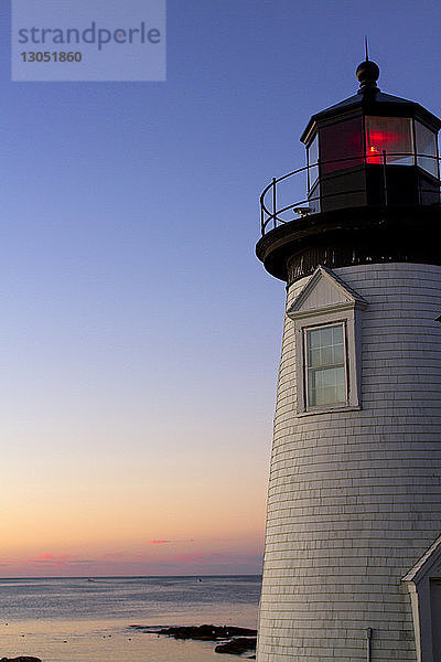 Niedrigwinkelansicht des Prospect Harbor Point Light gegen das Meer und den dramatischen Himmel bei Sonnenuntergang