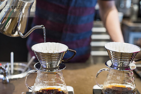 Barista gießt kochendes Wasser in Kaffeefilter im Café