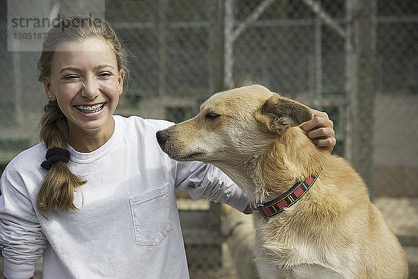 Glückliches Teenager-Mädchen mit Hund sitzt am Zaun im Banff-Nationalpark