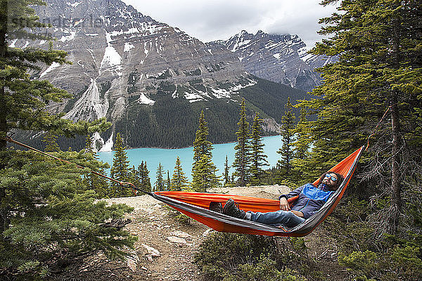 Hochwinkelaufnahme eines Wanderers  der sich in einer Hängematte am Peyto Lake und in den Bergen des Banff National Park ausruht