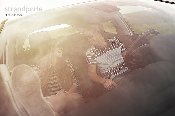 Paar redet  während es im Auto sitzt und durch die Windschutzscheibe gesehen wird