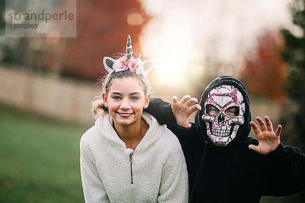 Geschwister in Halloween-Kostüm posieren im Park