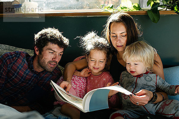 Eltern  die Kindern im Bett vorlesen