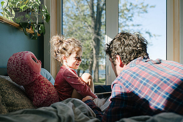 Vater und Tochter unterhalten sich im Bett