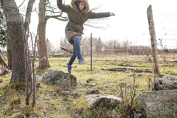 Mädchen springt im Feld von Fels zu Fels