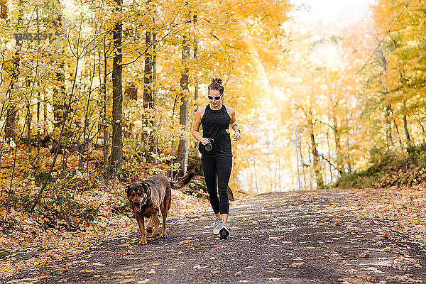 Frau joggt mit Hund im Wald