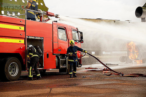 Ausbildung von Feuerwehrleuten  Versprühen von Wasser aus einem Löschfahrzeug an einer Flugzeugattrappe