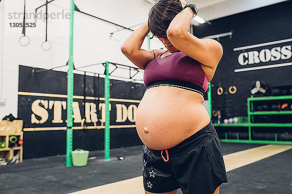 Schwangere Frau mit dem Kopf in der Hand im Fitnessstudio