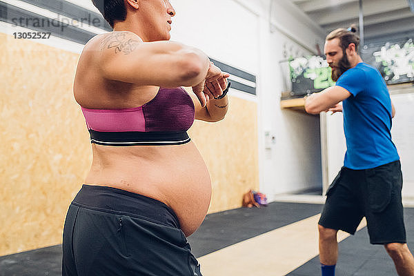 Schwangere Frau und Trainerin beim Aufwärmen im Fitnessstudio