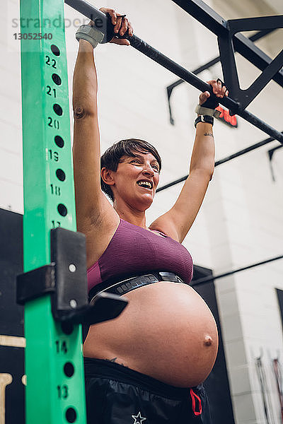 Schwangere Frau benutzt Gymnastikstange im Fitnessstudio