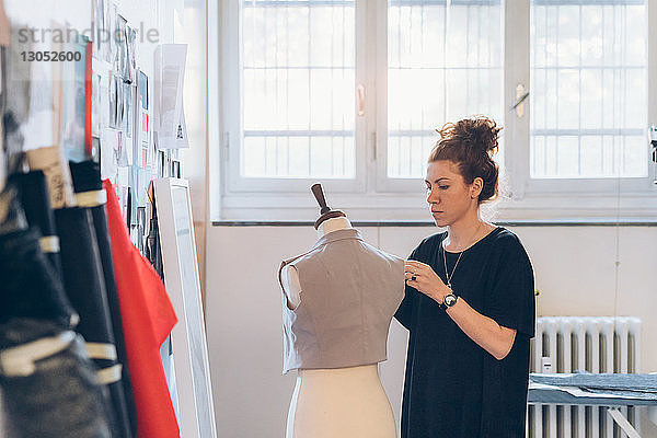 Modedesigner heftet Kleidungsstück an Schnullerpuppe der Schneiderin