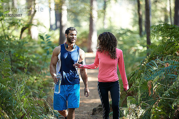 Männliche und weibliche Läufer teilen sich Flaschenwasser im Wald
