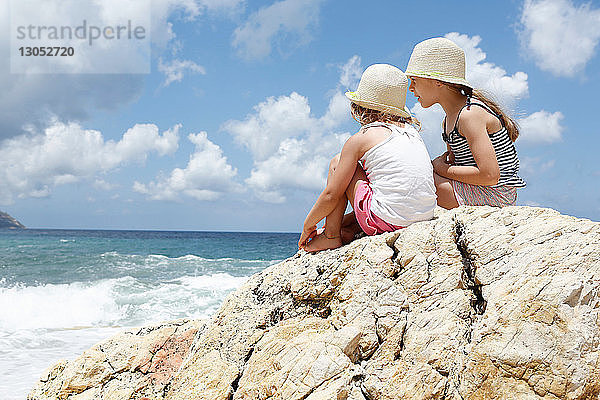 Zwei Mädchen schauen vom Felsen aufs Meer hinaus  Scopello  Sizilien  Italien