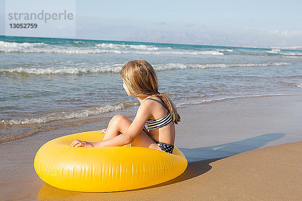 Mädchen sitzt auf einem gelben Schlauchboot am Strand  Castellammare del Golfo  Sizilien  Italien