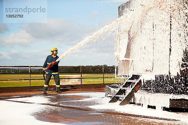 Ausbildung von Feuerwehrleuten  Feuerwehrmann versprüht Feuerlöschschaum in Trainingseinrichtung