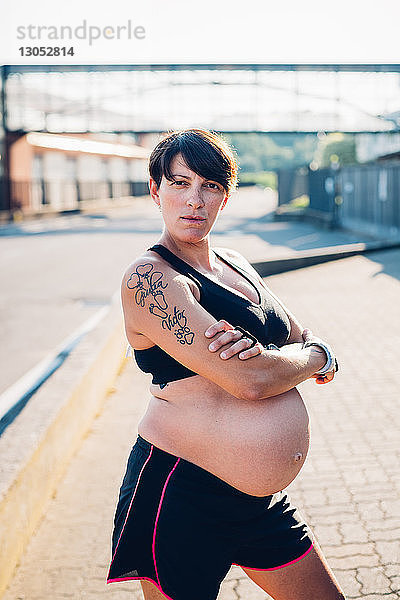 Schwangere Frau in Trainingskleidung bei Sonnenschein