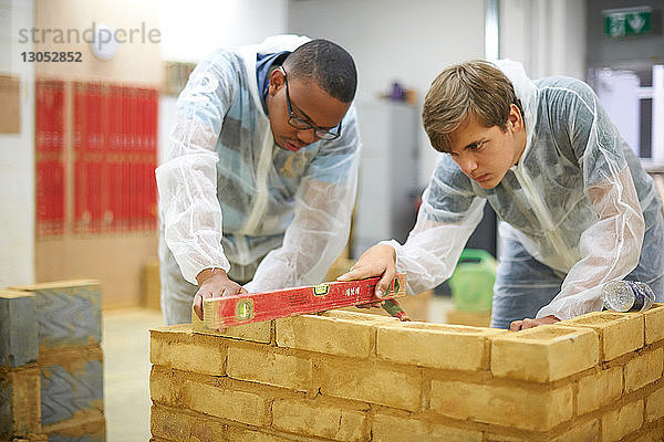 Männliche Hochschulstudenten bauen Backsteinmauer in College-Werkstatt