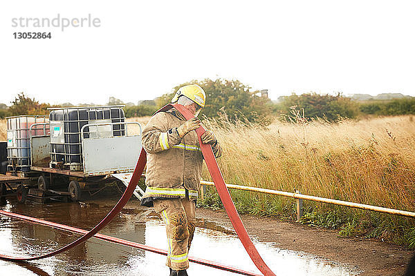 Ausbildung von Feuerwehrleuten  Feuerwehrmann mit Feuerwehrschlauch über der Schulter in der Ausbildungsstätte