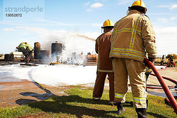 Ausbildung von Feuerwehrleuten  Team von Feuerwehrleuten  die Feuerlöschschaum in der Ausbildungseinrichtung versprühen