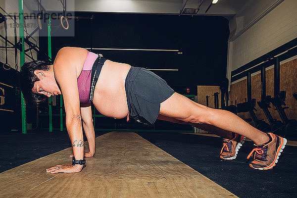 Schwangere Frau macht Liegestütze im Fitnessstudio