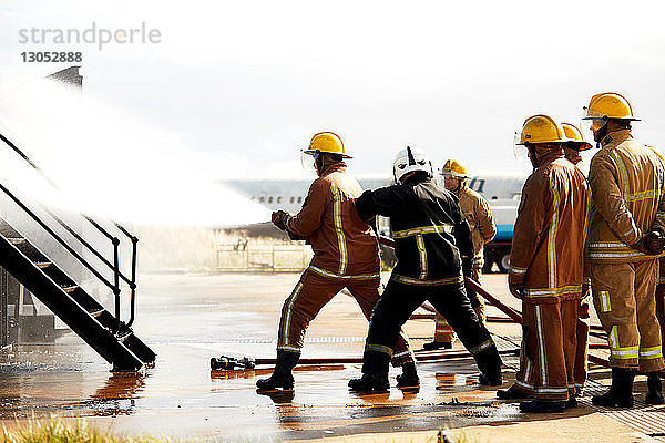 Ausbildung von Feuerwehrleuten  Feuerwehrmänner sprühen Wasser in der Ausbildungseinrichtung