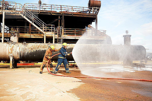 Ausbildung von Feuerwehrleuten  Feuerwehrmänner spritzen Wasser aus dem Feuerwehrschlauch in der Ausbildungseinrichtung