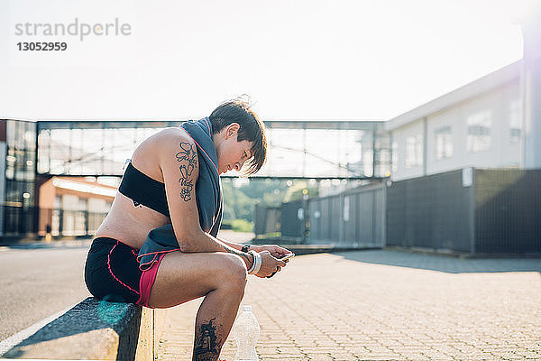 Schwangere Frau liest Textnachricht beim Training