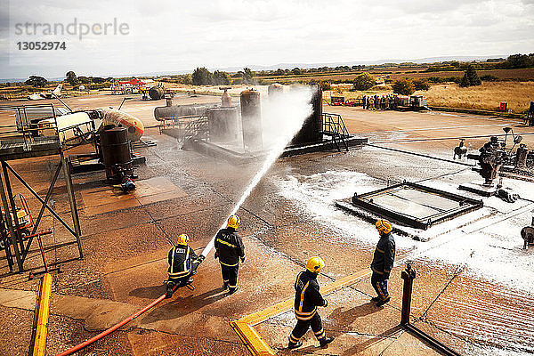 Ausbildung von Feuerwehrleuten  Feuerwehrmänner sprühen Feuerlöschschaum am Öllagertank der Ausbildungseinrichtung