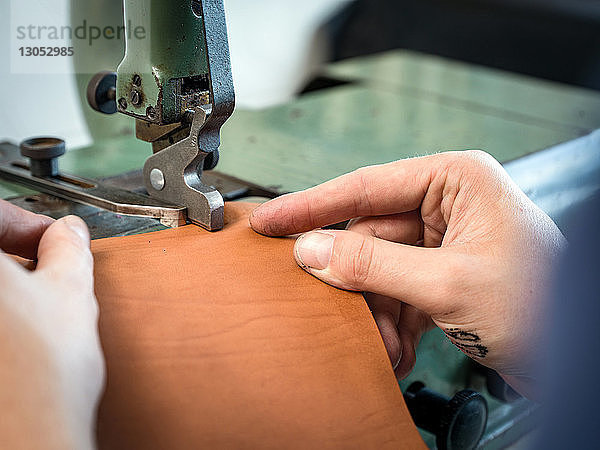 Lederarbeiter bei der Bearbeitung der Handtaschenkante aus Leder in der Werkstatt  Nahaufnahme der Hände