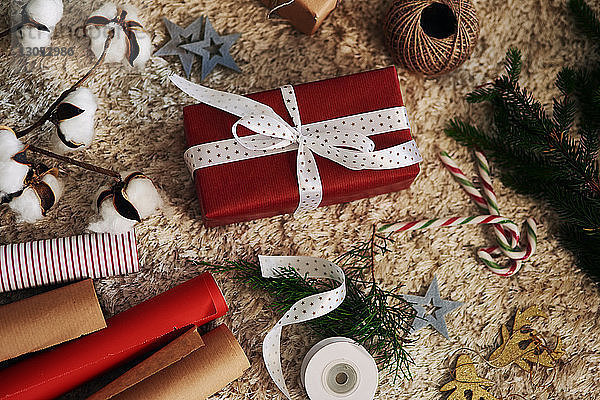Weihnachtsgeschenk  Geschenkpapier  Schnur und Glocken auf dem Teppich