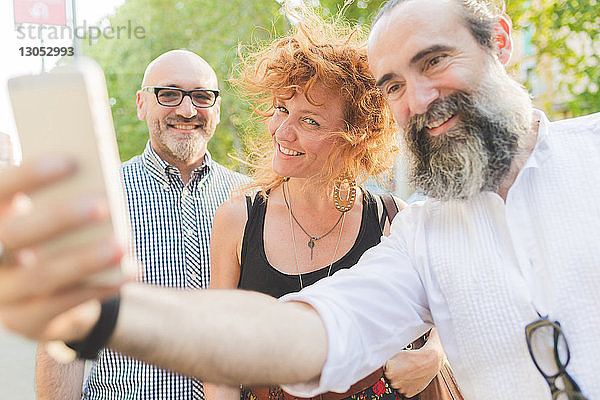 Mittelgroße erwachsene Frauen und männliche Freunde nehmen Smartphone-Selfie auf der Straße