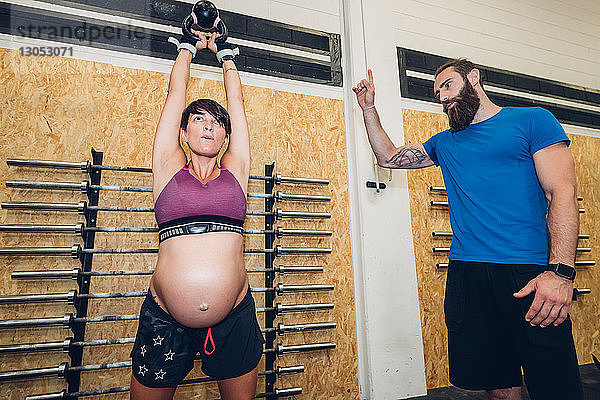 Schwangere Frau benutzt Kettlebell im Fitnessstudio