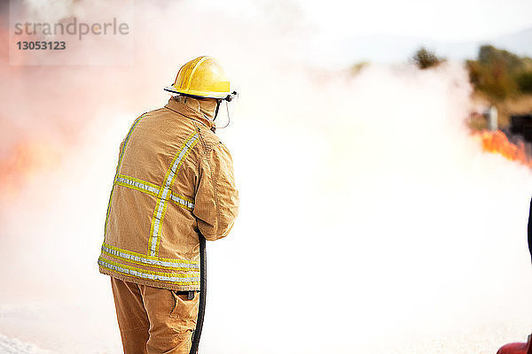 Ausbildung von Feuerwehrleuten  Feuerwehrmann versprüht Feuerlöschschaum in Trainingseinrichtung