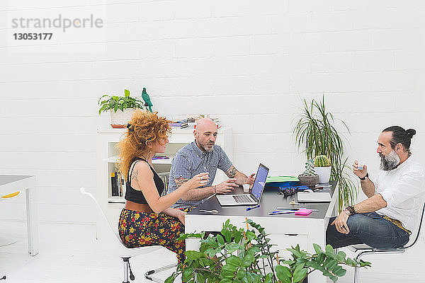 Geschäftsmänner und -frauen diskutieren bei Bürobesprechung