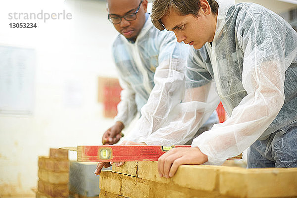 Männliche Hochschulstudenten bauen Backsteinmauer in College-Werkstatt