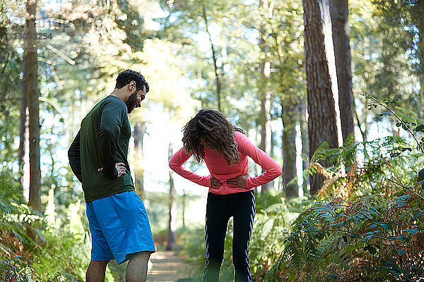 Erschöpfte Läufer und Läuferinnen machen eine Pause im Wald