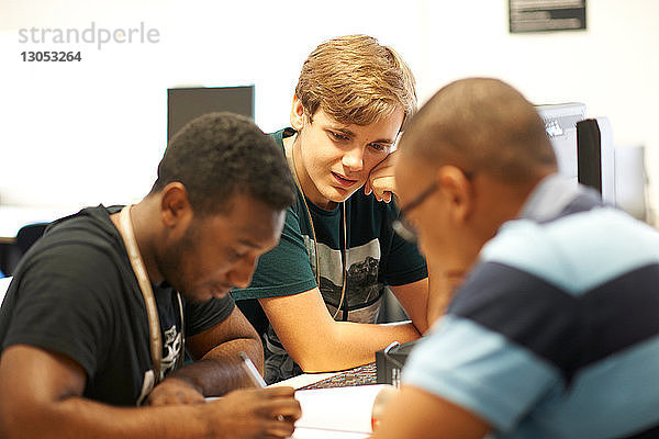 Männliche Hochschulstudenten betrachten Papierkram im College-Klassenzimmer